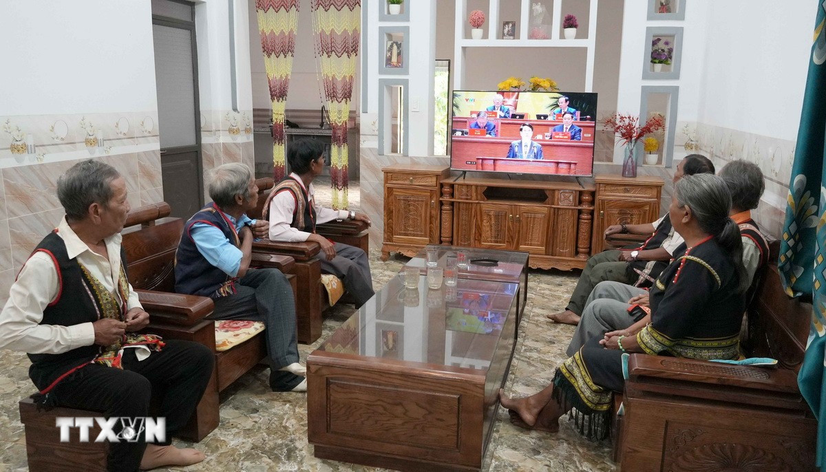 Già làng, người có uy tín và bà con làng Plei Jơ Drơp, xã Ia Chim, tỉnh Quảng Ngãi theo dõi phiên khai mạc Đại hội lần thứ XIV của Đảng. (Ảnh: Cao Nguyên/TTXVN)