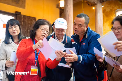 Các cử tri đến bỏ phiếu được thành viên tổ bầu cử hướng dẫn tận tình. (Ảnh: Minh Sơn/Vietnam+)