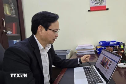 Tiến sỹ Nguyễn Đình Hoàng nghiên cứu thông tin về Đại hội Đại biểu toàn quốc lần thứ XIV của đảng trên website của Thông tấn xã Việt Nam. (Ảnh: Minh Thu/TTXVN)