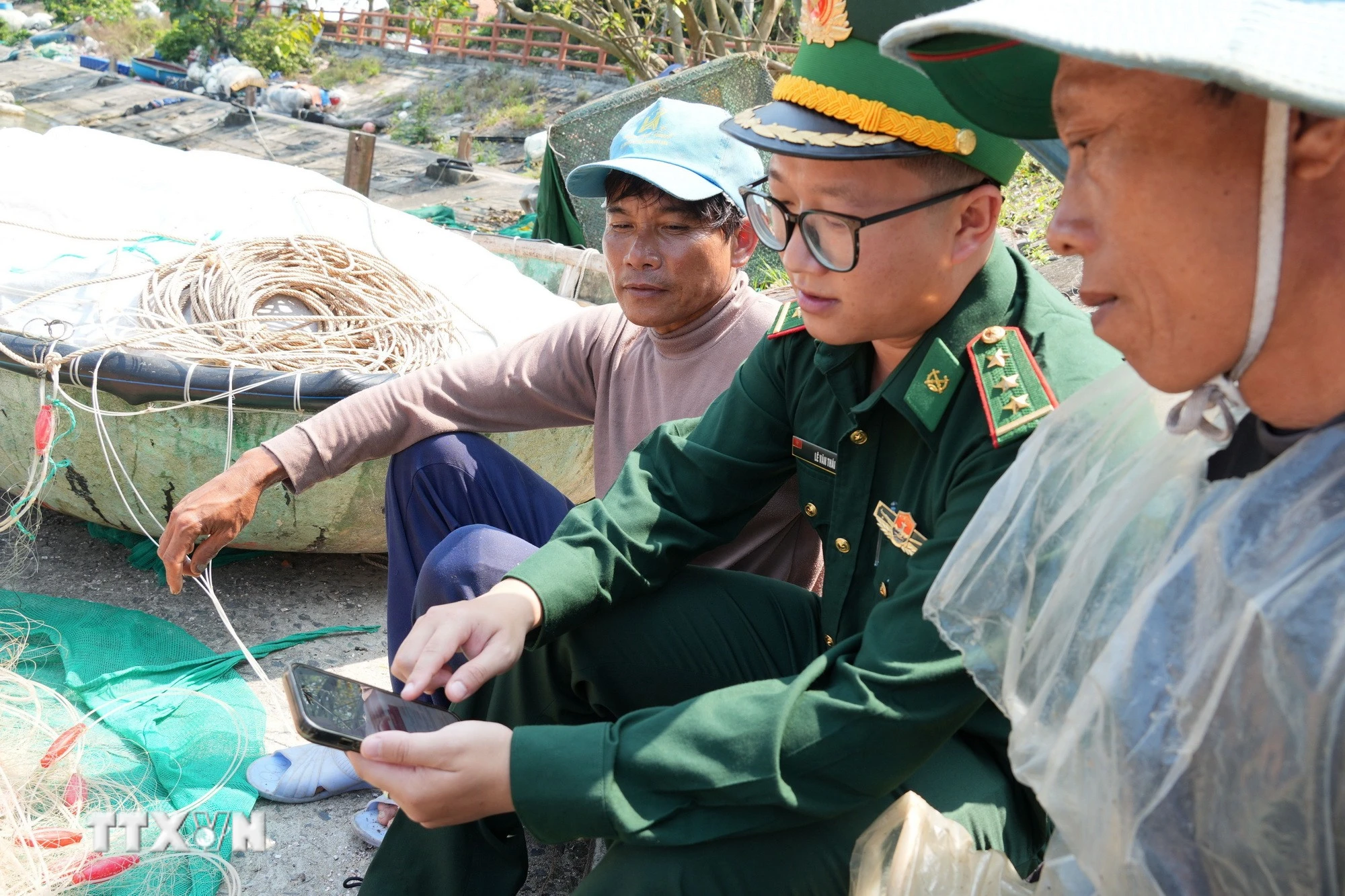 Bộ đội Biên phòng và ngư dân tại đảo Cù Lao Chàm (xã Tân Hiệp, thành phố Đà Nẵng) theo dõi thông tin về bầu cử trên điện thoại. (Ảnh: Anh Dũng/TTXVN)