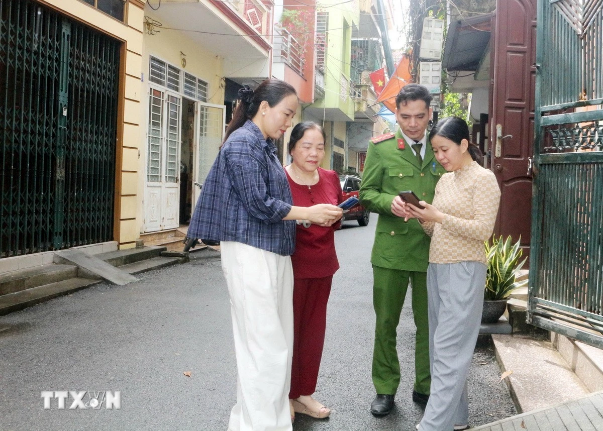 Tổ công nghệ số cộng đồng cùng cán bộ công an phường Phủ Lý, tỉnh Ninh Bình đến từng khu dân cư hướng dẫn người dân tham gia góp ý dự thảo các văn kiện Đại hội XIV của Đảng thông qua ứng dụng VNeID. (Ảnh: Nguyễn Chinh/TTXVN)