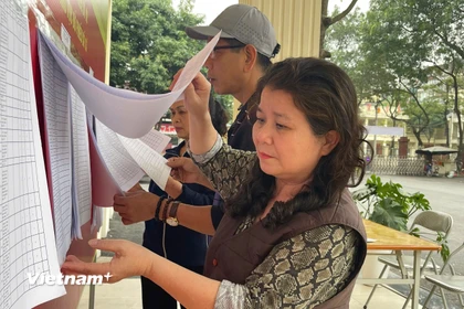 Cử tri phường Từ Liêm kiểm tra danh sách cử tri được niêm yết công khai tại khu vực bỏ phiếu. (Ảnh: Hằng Trần/Vietnam+)