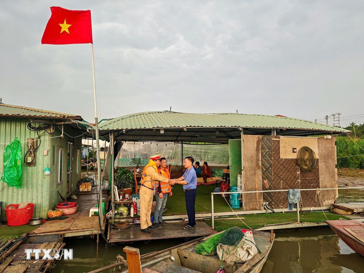 Đội Cảnh sát đường thủy số 2, Phòng Cảnh sát giao thông (Công an thành phố Hà Nội) đi từng xóm, đón từng thuyền, phát thẻ cử tri cho người dân trên sông Hồng. (Ảnh: TTXVN phát)