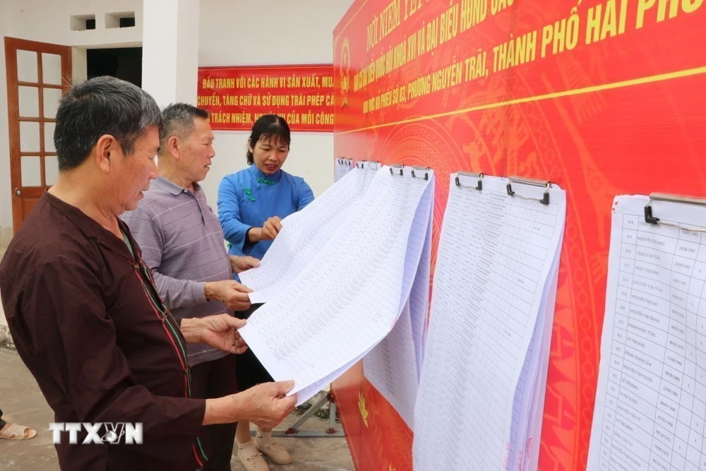 Người dân xem danh sách cử tri được niêm yết. (Ảnh: Mạnh Minh/TTXVN)