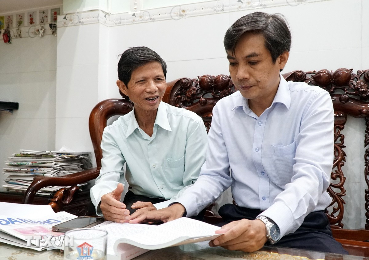 Ông Phạm Công Lương, Bí thư Chi bộ Khu dân cư Bình Phước 1, phường Hải Châu, thành phố Đà Nẵng (bên trái) chia sẻ cảm nhận về dự thảo Văn kiện Đại hội với cán bộ phường Hải Châu. (Ảnh: Quốc Dũng/TTXVN)