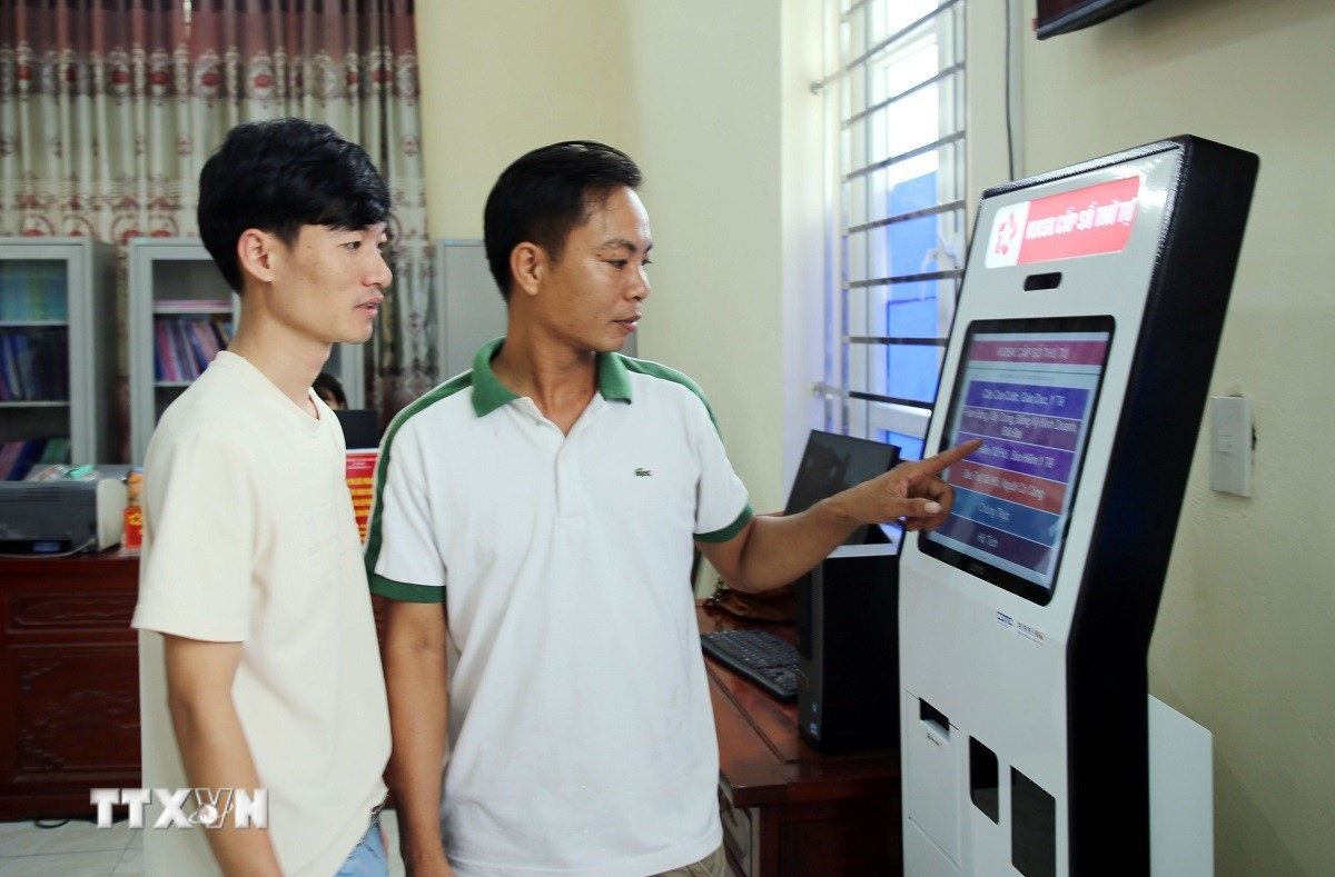 Người dân xã Yên Mô lấy số thứ tự giải quyết thủ tục hành chính. (Ảnh: Nguyễn Lành/TTXVN)