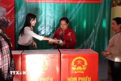 Thành viên tổ bầu cử nhiệt tình hỗ trợ, hướng dẫn cử tri các bước bỏ phiếu đúng quy định. (Ảnh: Trung Kiên/TTXVN)