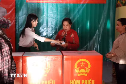 Thành viên tổ bầu cử nhiệt tình hỗ trợ, hướng dẫn cử tri các bước bỏ phiếu đúng quy định. (Ảnh: Trung Kiên/TTXVN)