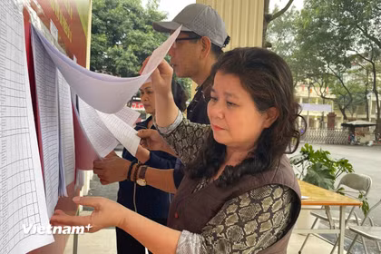Cử tri phường Từ Liêm kiểm tra danh sách cử tri được niêm yết công khai tại khu vực bỏ phiếu. (Ảnh: Hằng Trần/Vietnam+)