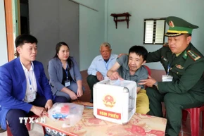 Tổ bầu cử số 2 bản Luốc Làu, xã vùng cao biên giới Mường Mìn mang hòm phiếu lưu động hỗ trợ cho cử tri khuyết tật vận động Vi Văn Lui thực hiện quyền bầu cử.