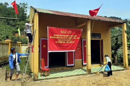 Bà con đồng bào Bru-Vân Kiều (bản Nước Đắng, xã Trường Sơn, Quảng Trị) trang trí khu vực bỏ phiếu, chuẩn bị sẵn sàng cho việc bỏ phiếu sớm vào ngày 8/3. (Ảnh: TTXVN phát)