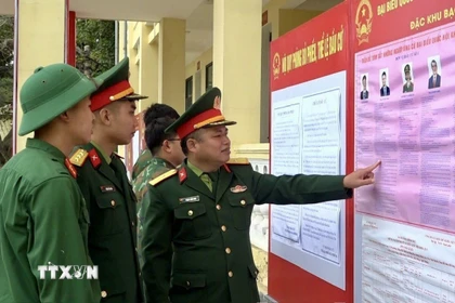 Cán bộ, chiến sỹ Tiểu đoàn phòng thủ đảo Bạch Long Vĩ đang xem tiểu sử tóm tắt những người ứng cử đại biểu Quốc hội khóa XVI. (Ảnh: TTXVN phát)